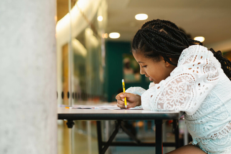 Child writing with NewsWise pencil